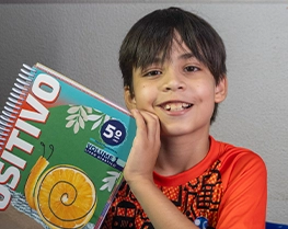 Aluno sorrindo com seu livro